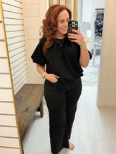 Load image into Gallery viewer, Woman wearing Vervet Olivia black crop jeans with a black flutter sleeve top, showing the full front fit.